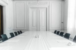 A photo of an empty white wall with white doors in the background, furnished as seminar room or congress